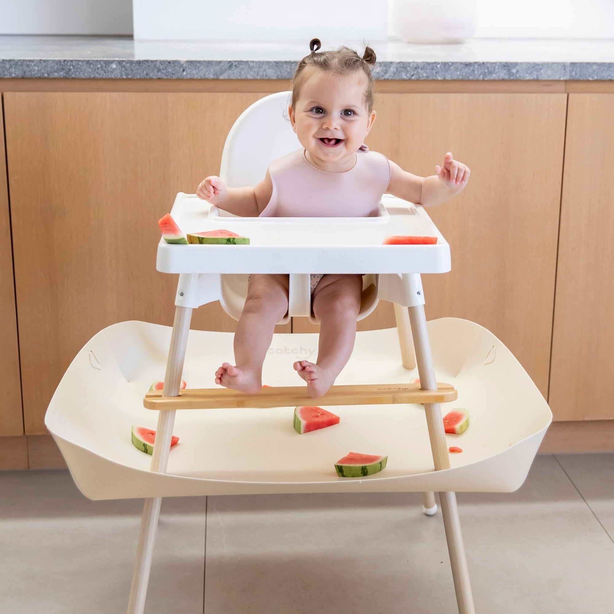 Baby eating watermelon in high chair with mess-catching tray, food-safe and easy clean design